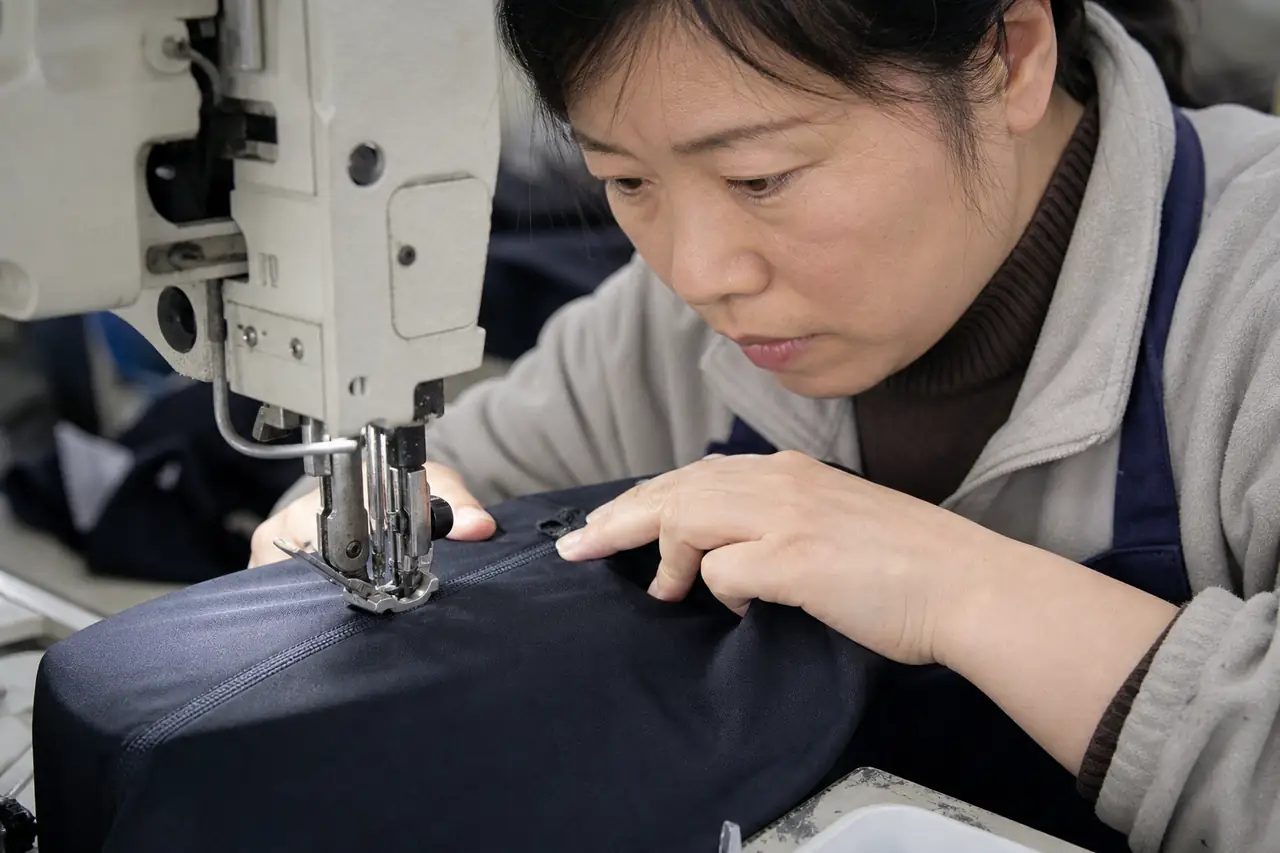 Chinese sewing operator inspecting technical garment seam formation